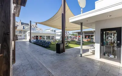 a patio with awning and tables and chairs at Clareon By The Coast by Oversee 30A in Seacrest