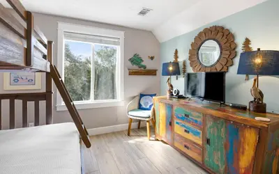 a bedroom with a dresser with a mirror and a bunk bed at Clareon By The Coast by Oversee 30A in Seacrest