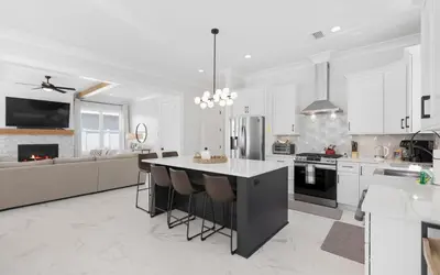a kitchen with white cabinets and a large island with bar stools at Coconut Cove by Oversee 30A in Santa Rosa Beach