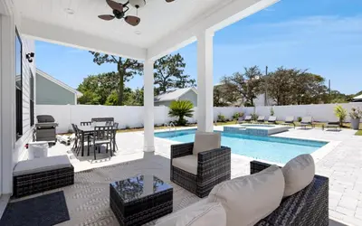 an outdoor patio with a pool and a table and chairs at Coconut Cove by Oversee 30A in Santa Rosa Beach