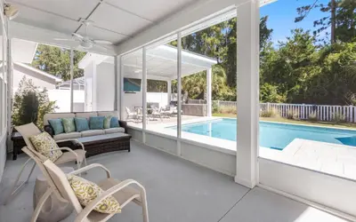 an outdoor patio with a pool and chairs and a couch at Coral Retreat by Oversee 30A in Seacrest