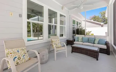 a screened porch with chairs and a couch at Coral Retreat by Oversee 30A in Seacrest