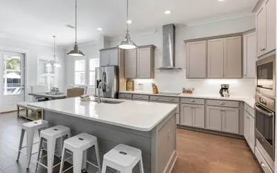 a kitchen with white cabinets and a large island with stools at Coral Retreat by Oversee 30A in Seacrest