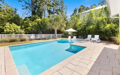 a swimming pool with two chairs and an umbrella at Coral Retreat by Oversee 30A in Seacrest