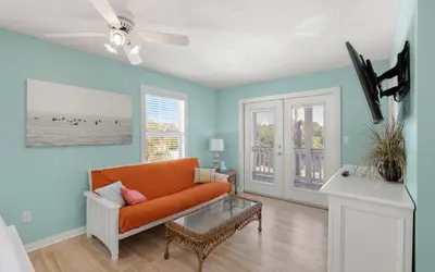 a living room with an orange couch and blue walls at Dolphin Run by Oversee 30A in Santa Rosa Beach