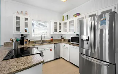 a kitchen with white cabinets and a stainless steel refrigerator at Dolphin Run by Oversee 30A in Santa Rosa Beach