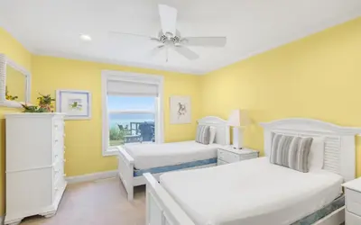 two beds in a room with yellow walls and a window at Family Ties by Oversee 30A in Santa Rosa Beach