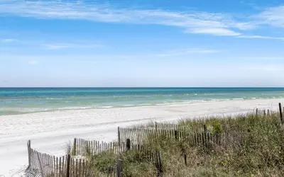 a beach with a fence and the ocean at Family Ties by Oversee 30A in Santa Rosa Beach