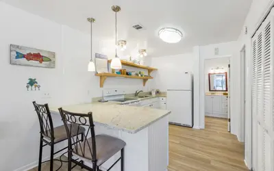 a kitchen with two bar stools and a counter at Go Coastal by Oversee 30A in Santa Rosa Beach