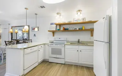 a kitchen with white cabinets and a white refrigerator at Go Coastal by Oversee 30A in Santa Rosa Beach