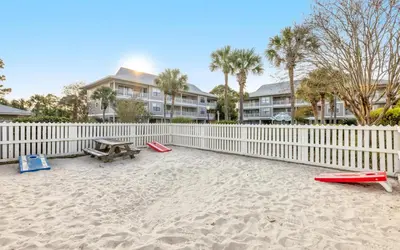 a picnic table on the beach next to a fence at Go Coastal by Oversee 30A in Santa Rosa Beach