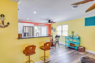 a kitchen and living room with yellow walls and wooden floors at Panama City Home with Fire Pit - Walk to Beaches! in Panama City Beach
