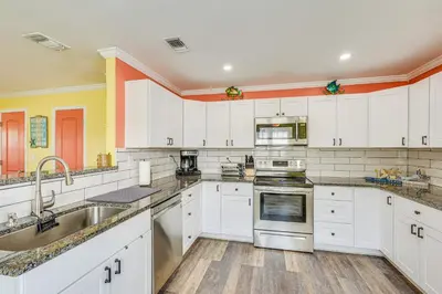 a kitchen with white cabinets and stainless steel appliances at Panama City Home with Fire Pit - Walk to Beaches! in Panama City Beach