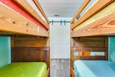 two bunk beds in a room with a door at Panama City Home with Fire Pit - Walk to Beaches! in Panama City Beach