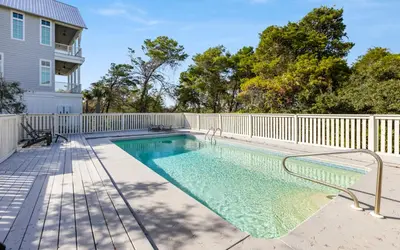 a swimming pool next to a white fence at Hideaway Cottage by Oversee 30A in Inlet Beach