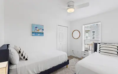 a white bedroom with two beds and a window at Hideaway Cottage by Oversee 30A in Inlet Beach
