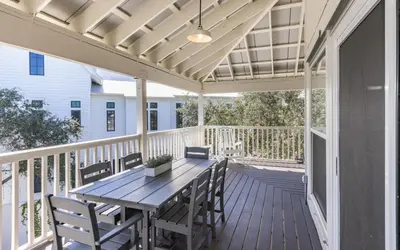 a patio with a wooden table and chairs on a deck at Hideaway Cottage by Oversee 30A in Inlet Beach