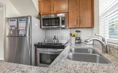 a kitchen with a sink and a stainless steel refrigerator at Holzworth House by Oversee 30A in Santa Rosa Beach