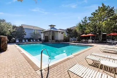 a swimming pool with chairs and tables and a house at Inlet Beach Cottage by Oversee 30A in Inlet Beach
