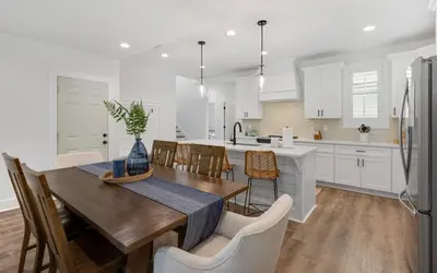 a kitchen with white cabinets and a wooden table and chairs at Inlet Beach Paradise by Oversee 30A in Inlet Beach