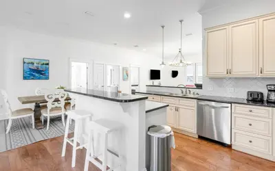 a kitchen with white cabinets and a table and chairs at Instant Gratification by Oversee 30A in Santa Rosa Beach