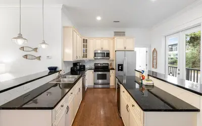 a large kitchen with white cabinets and black counter tops at Instant Gratification by Oversee 30A in Santa Rosa Beach