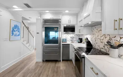 a kitchen with white cabinets and a stainless steel refrigerator at Into the Mystic by Oversee 30A in Seacrest