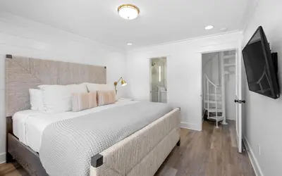 a white bedroom with a large bed and a flat screen tv at Into the Mystic by Oversee 30A in Seacrest