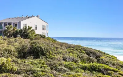 a white house on a hill next to the ocean at Legacy 201 Emerald Beach by Oversee 30A in Santa Rosa Beach