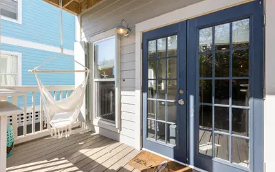 a porch with blue doors and a hammock at Lemon Squeezy by Oversee 30A in Inlet Beach