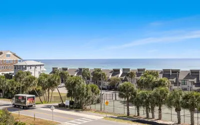 a bus driving down a street next to a beach at Lemon Squeezy by Oversee 30A in Inlet Beach