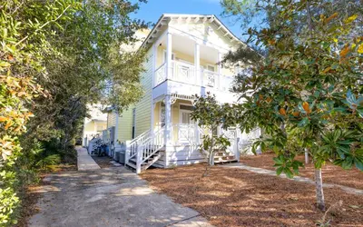 a white house with trees in front of it at Mellow Yellow by Oversee 30A in Santa Rosa Beach