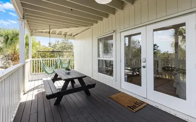 a wooden deck with a picnic table on a porch at Mystic Cottage by Oversee 30A in Inlet Beach