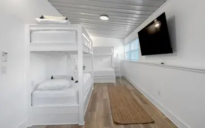 a room with white bunk beds and a flat screen tv at Mystic Cottage by Oversee 30A in Inlet Beach