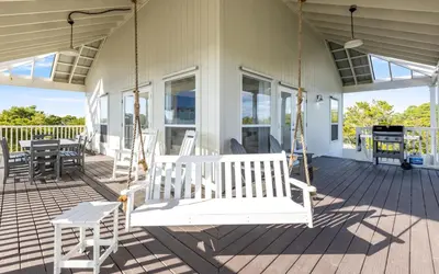 a porch swing on the front of a house at Mystic Cottage by Oversee 30A in Inlet Beach