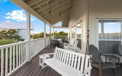 a porch with rocking chairs and a swing at Mystic Cottage by Oversee 30A in Inlet Beach