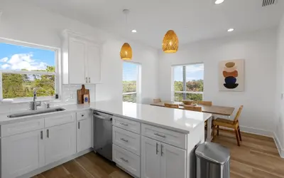 a white kitchen with a sink and a table at Mystic Cottage by Oversee 30A in Inlet Beach