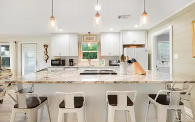 a kitchen with a large marble counter top and stools at Noras Place by Oversee 30A in Santa Rosa Beach