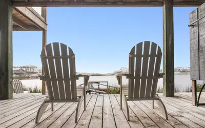 two chairs and a table on a deck with the water at Noras Place by Oversee 30A in Santa Rosa Beach
