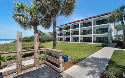 a building with palm trees and a bench in front of it at Palms of Seagrove A8 by Oversee 30A in Santa Rosa Beach