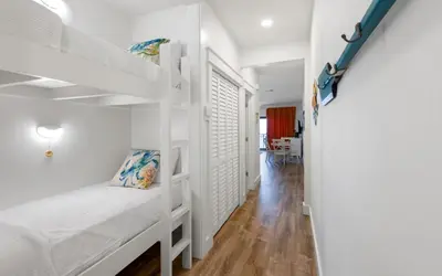 a room with white bunk beds and a hallway at Palms of Seagrove A8 by Oversee 30A in Santa Rosa Beach