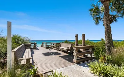 a wooden walkway to the beach with benches and a palm tree at Palms of Seagrove A8 by Oversee 30A in Santa Rosa Beach