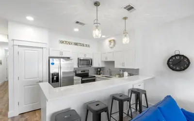 a kitchen with white cabinets and a counter with stools at Palms of Seagrove A8 by Oversee 30A in Santa Rosa Beach