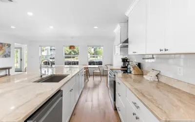 a kitchen with white cabinets and a wooden floor at Palms on Pelican by Oversee 30A in Seacrest