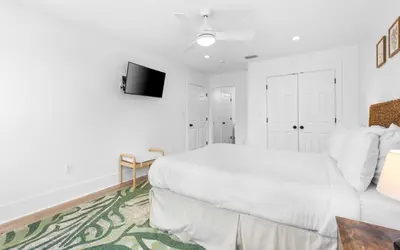 a white bedroom with a bed and a tv at Palms on Pelican by Oversee 30A in Seacrest