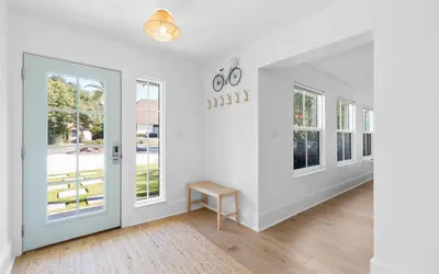 a hallway with white walls and a door and windows at Palms on Pelican by Oversee 30A in Seacrest