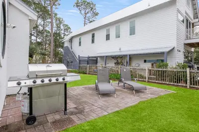 a backyard with a grill and chairs and a house at Peace of Mind by Oversee 30A in Santa Rosa Beach