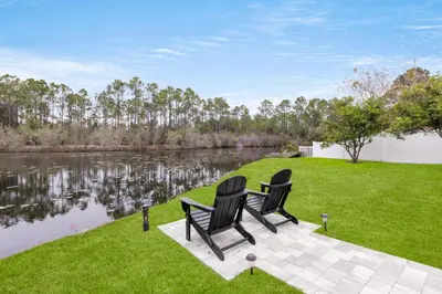 two black chairs sitting on a patio next to a lake at Peace of Mind by Oversee 30A in Santa Rosa Beach