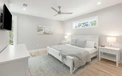 a white bedroom with a bed and a ceiling fan at Sand Juan by Oversee 30A in Santa Rosa Beach
