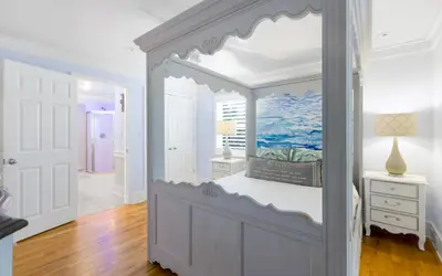 a white bedroom with a canopy bed and a desk at SeaGroovInn by Oversee 30A in Santa Rosa Beach